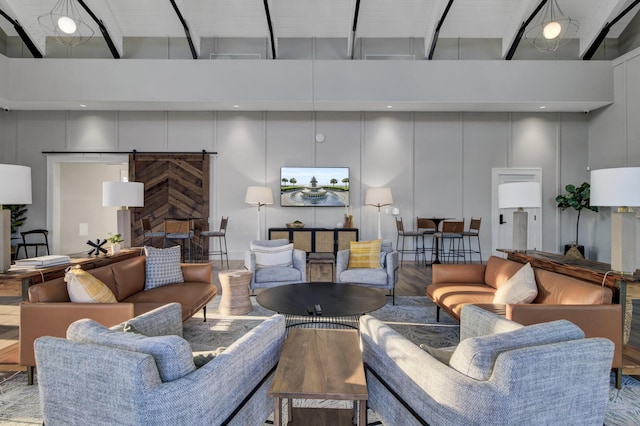 living room featuring wood finished floors, a towering ceiling, and a decorative wall