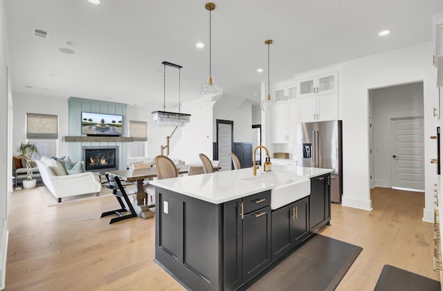 kitchen with visible vents, light countertops, white cabinets, high end fridge, and a sink