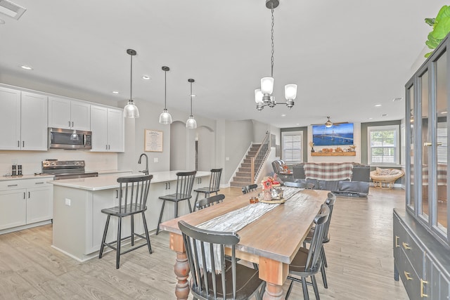 dining space featuring light wood-type flooring and an inviting chandelier