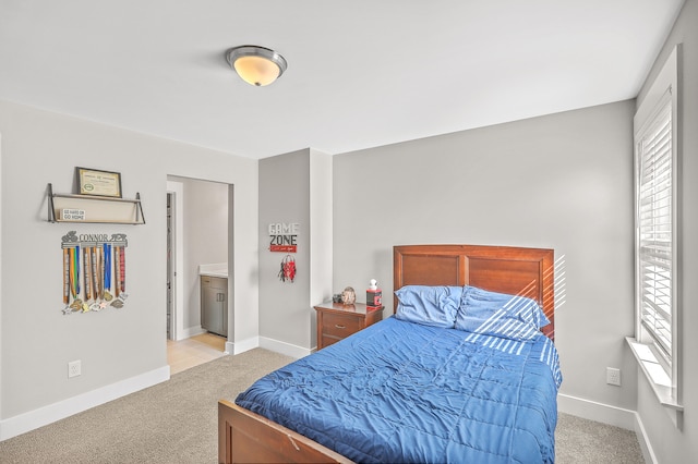 carpeted bedroom featuring ensuite bath and multiple windows