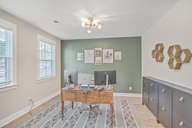 office space featuring plenty of natural light, an inviting chandelier, and light hardwood / wood-style floors