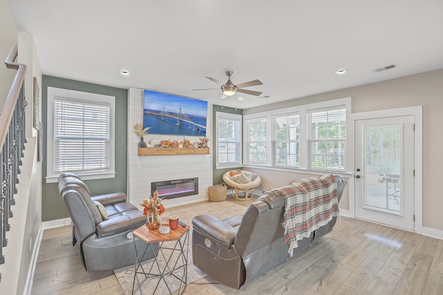 living room featuring a fireplace, light hardwood / wood-style flooring, and ceiling fan