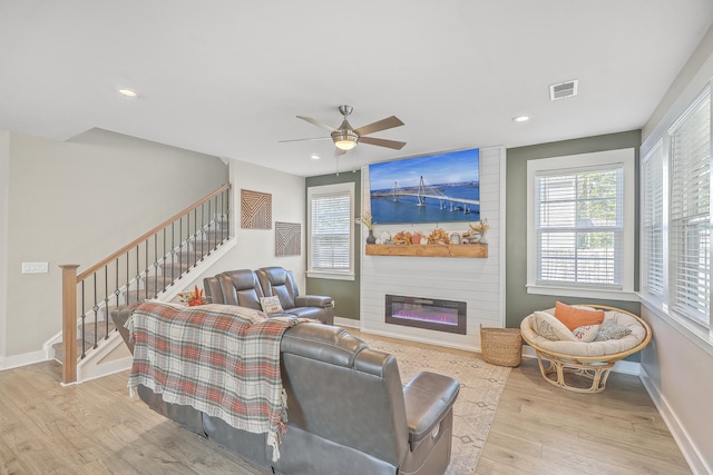 living room with a fireplace, light hardwood / wood-style flooring, and ceiling fan