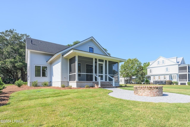 rear view of house featuring a yard and a sunroom