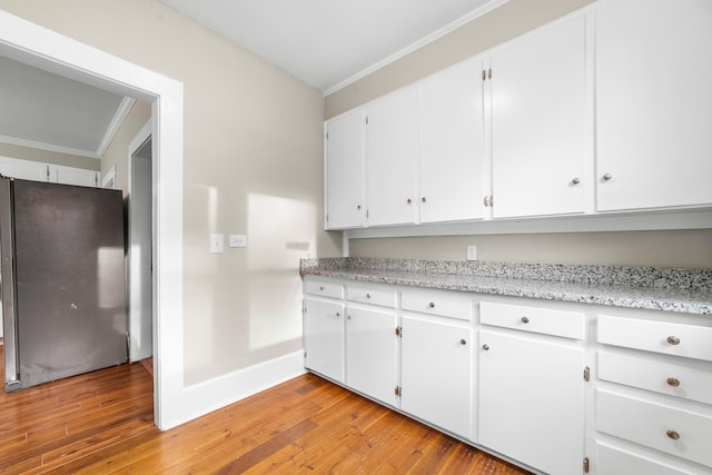 kitchen featuring stainless steel refrigerator, crown molding, light hardwood / wood-style flooring, and white cabinets