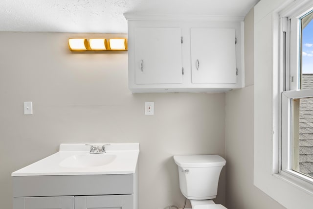 bathroom featuring vanity, a healthy amount of sunlight, and toilet