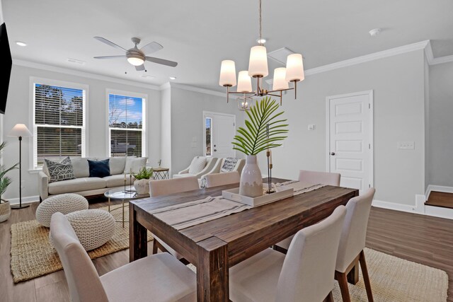 dining room with ceiling fan with notable chandelier, ornamental molding, and hardwood / wood-style floors