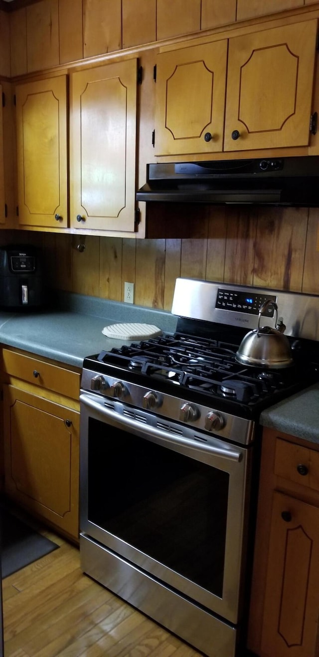 107 Kelly St, Walterboro, SC 29488 - kitchen featuring under cabinet range hood, brown cabinetry, light wood-style flooring, and gas range