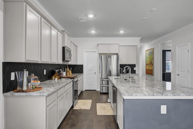 kitchen featuring visible vents, dark wood finished floors, ornamental molding, stainless steel appliances, and a sink