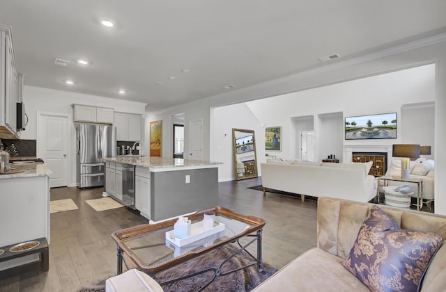 living area with dark wood-type flooring, recessed lighting, crown molding, and visible vents