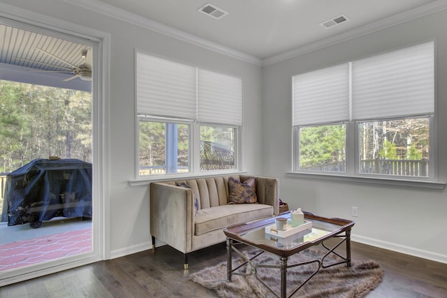 living area with a healthy amount of sunlight, wood finished floors, visible vents, and ornamental molding