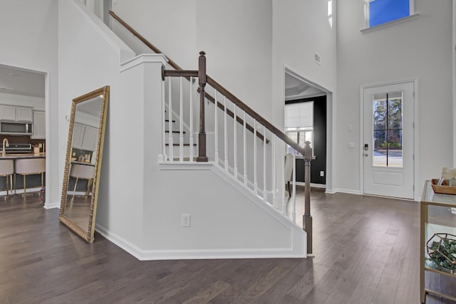 foyer featuring stairway, baseboards, a high ceiling, and wood finished floors