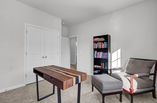 office area featuring baseboards and light carpet