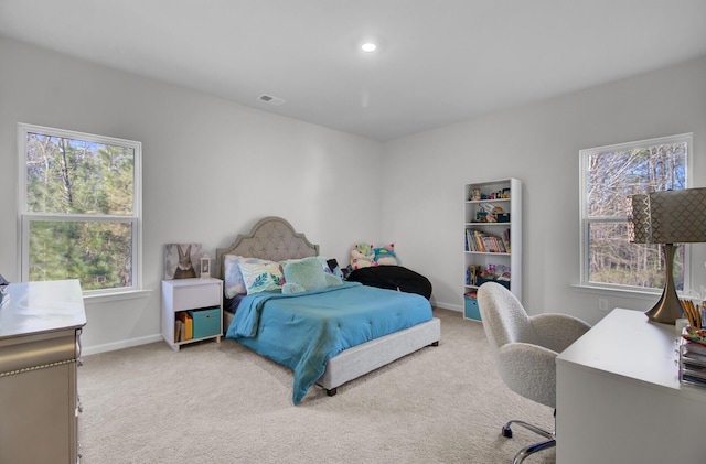 bedroom with multiple windows, light colored carpet, visible vents, and baseboards