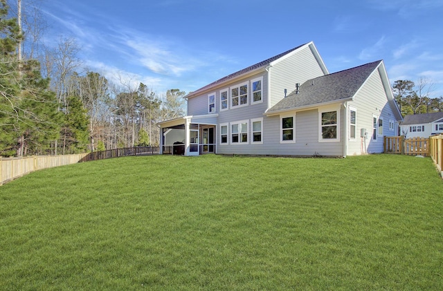 rear view of house with a lawn, roof with shingles, a fenced backyard, and a sunroom