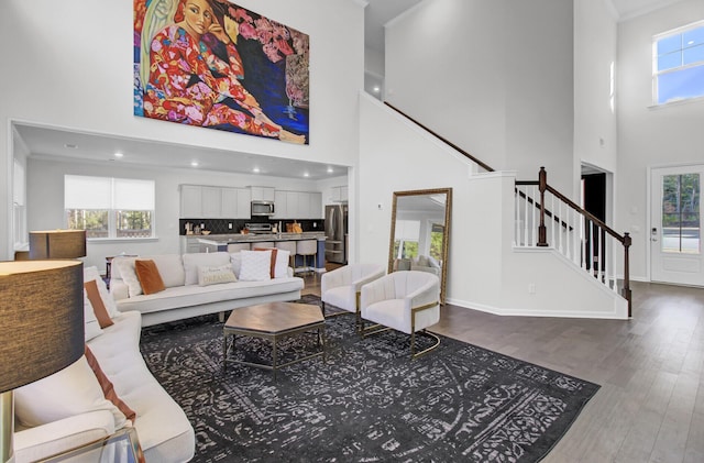 living room featuring stairs, crown molding, wood finished floors, and baseboards