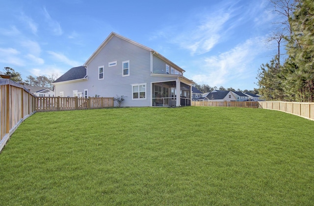 back of property featuring a lawn, a fenced backyard, and a sunroom