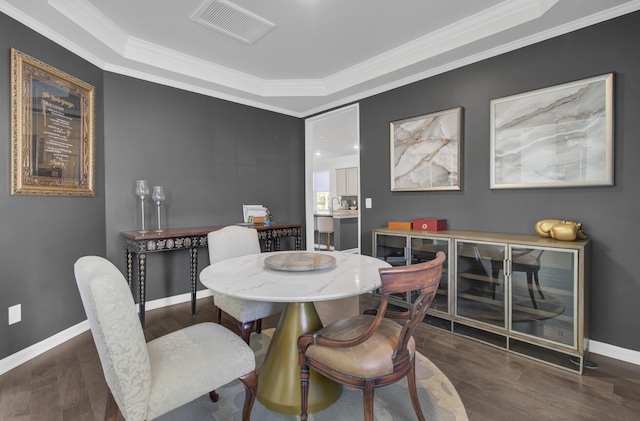 dining space featuring baseboards, wood finished floors, visible vents, and ornamental molding