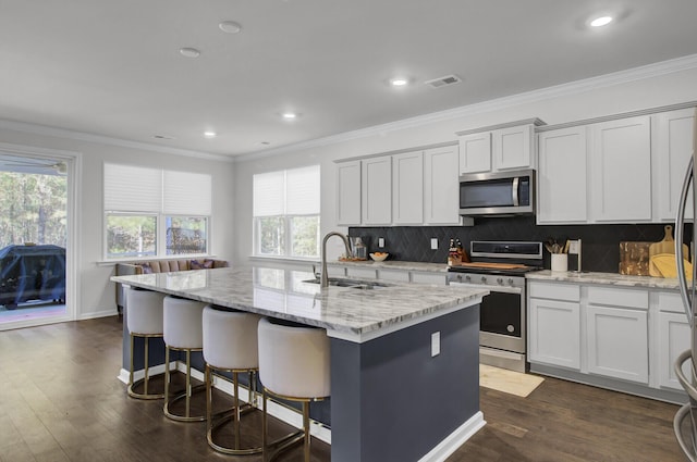 kitchen featuring visible vents, appliances with stainless steel finishes, crown molding, and a sink