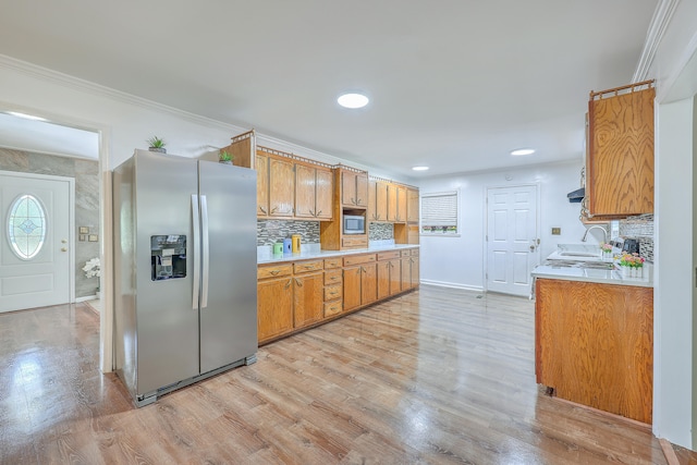 kitchen with light hardwood / wood-style floors, sink, stainless steel appliances, backsplash, and crown molding