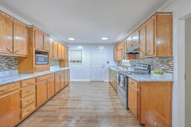 kitchen featuring appliances with stainless steel finishes, backsplash, light hardwood / wood-style floors, and sink