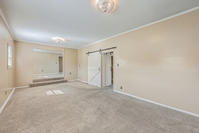 spare room with light carpet, crown molding, and a barn door