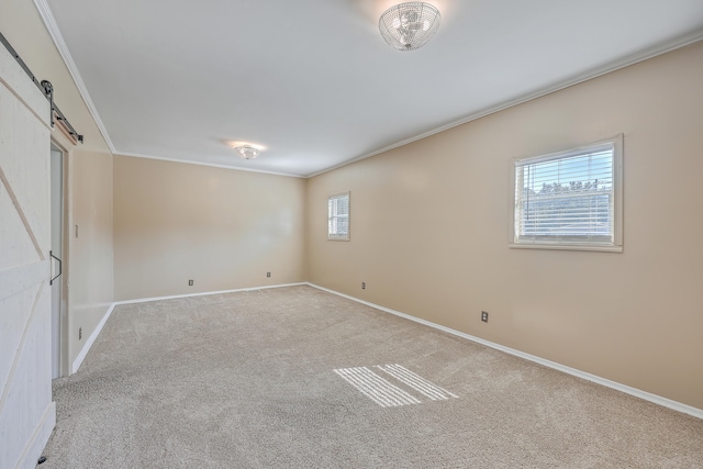 carpeted empty room featuring crown molding and a barn door