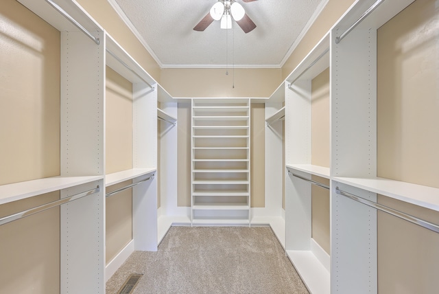 spacious closet with ceiling fan and light colored carpet