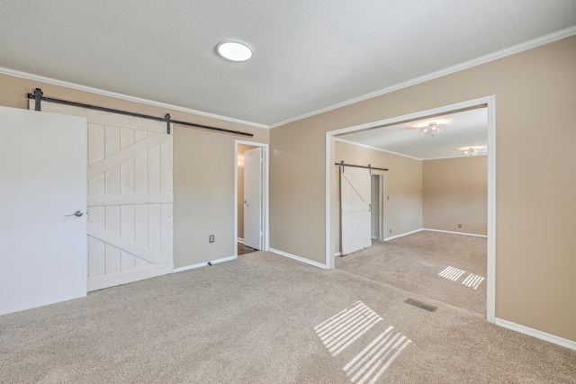 unfurnished bedroom with a textured ceiling, a closet, carpet floors, crown molding, and a barn door