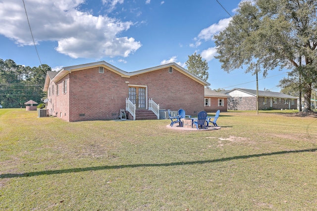 rear view of property featuring cooling unit, a lawn, a patio area, and an outdoor fire pit