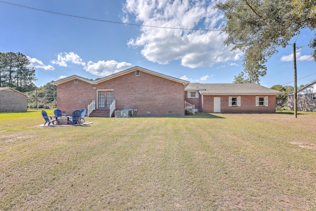 rear view of property featuring central AC unit, a yard, and an outdoor fire pit