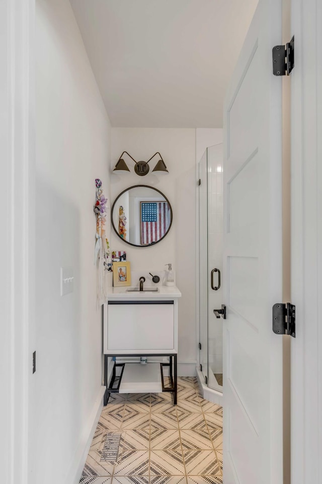 bathroom with vanity, a shower stall, and baseboards