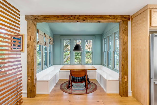 dining room with light wood-style flooring, vaulted ceiling with beams, and breakfast area