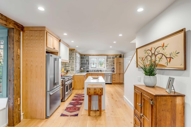 kitchen featuring light wood-style flooring, premium appliances, backsplash, recessed lighting, and light countertops