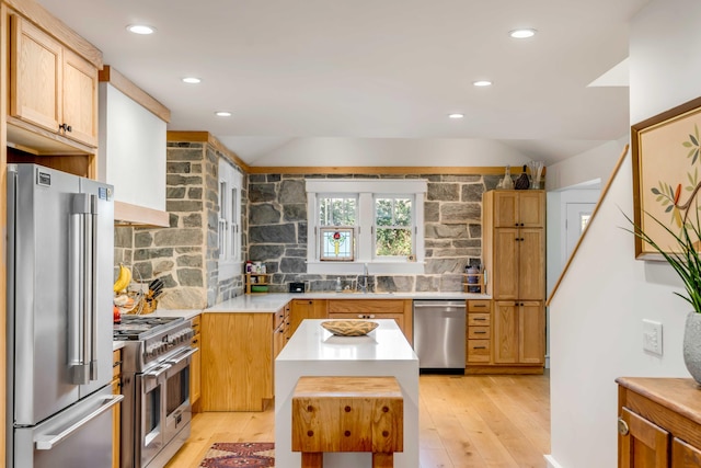 kitchen featuring backsplash, high quality appliances, light countertops, and a sink