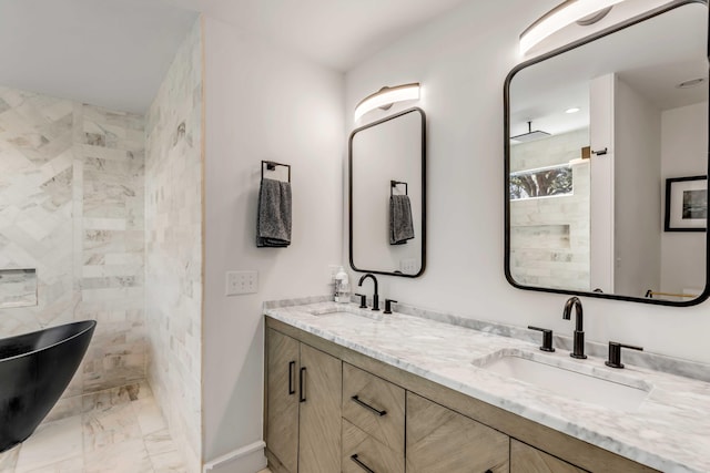 full bath featuring double vanity, marble finish floor, a tile shower, and a sink