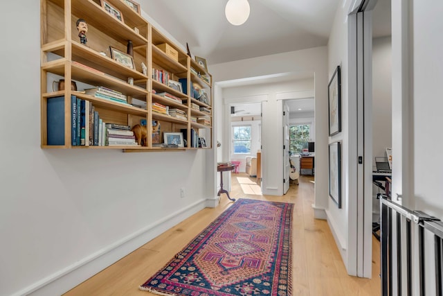 hall featuring light wood-style flooring and baseboards