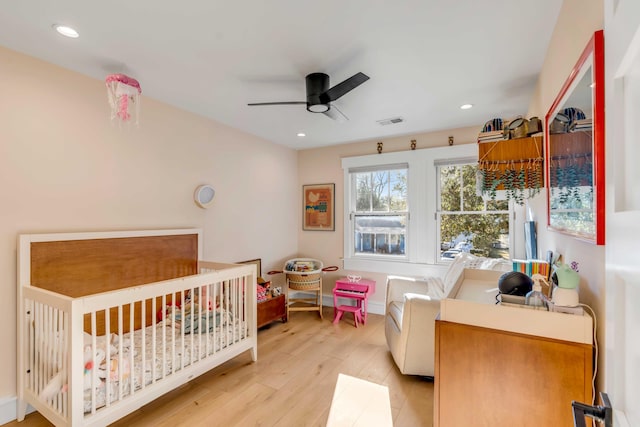 bedroom featuring recessed lighting, visible vents, a crib, and light wood-style floors