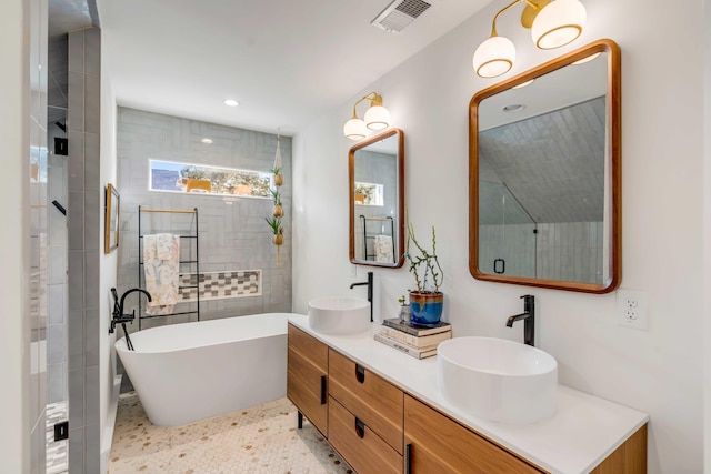 full bathroom with visible vents, a freestanding bath, tiled shower, and a sink