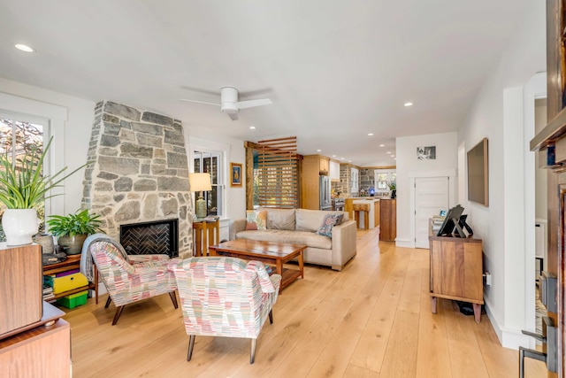 living area featuring a ceiling fan, recessed lighting, a fireplace, and light wood-style floors