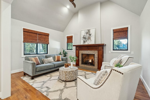 living area featuring baseboards, a premium fireplace, high vaulted ceiling, and wood finished floors