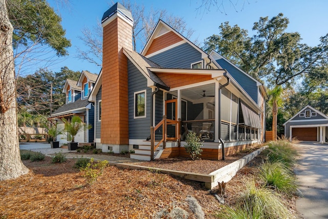 view of front of home featuring a garage, a sunroom, a chimney, crawl space, and an outdoor structure