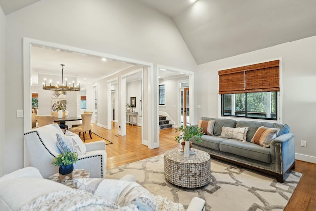 living area featuring a chandelier, light wood-style flooring, baseboards, stairs, and ornamental molding