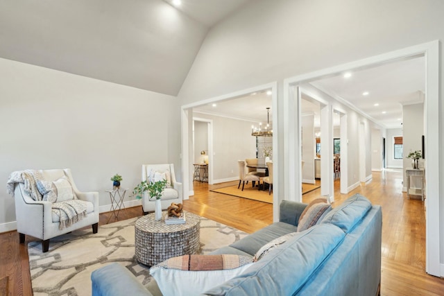 living area with a notable chandelier, light wood-style flooring, ornamental molding, high vaulted ceiling, and baseboards