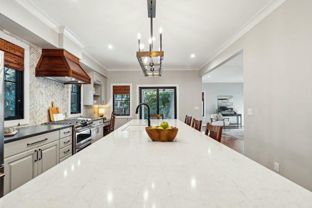 kitchen with decorative backsplash, ornamental molding, a sink, light stone countertops, and high end range