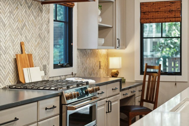 kitchen with gas stove, white cabinets, dark countertops, and decorative backsplash