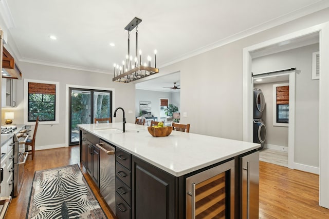 kitchen with wine cooler, stacked washer and dryer, light wood-style flooring, a barn door, and a sink