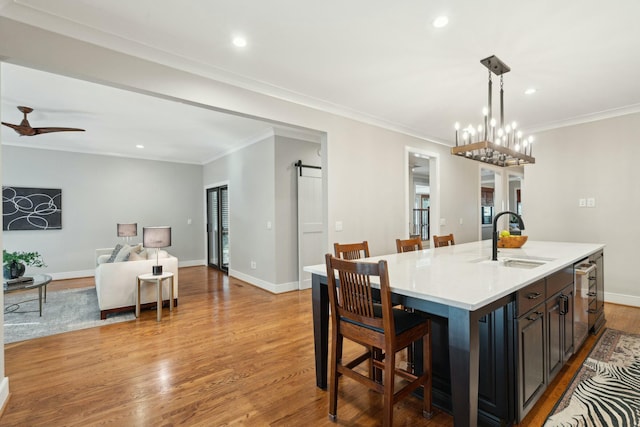 dining area featuring ornamental molding, light wood-style flooring, baseboards, and a barn door