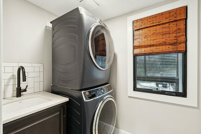 laundry area featuring stacked washing maching and dryer, cabinet space, visible vents, and a sink