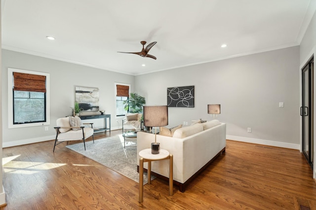 living room featuring a healthy amount of sunlight, crown molding, visible vents, and wood finished floors